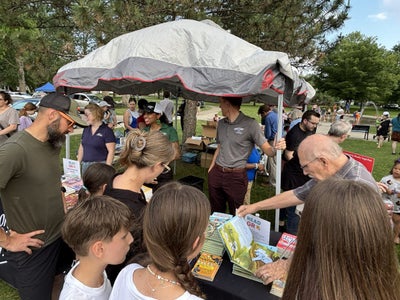 Volunteers and families at the Storytime in the Park book tables