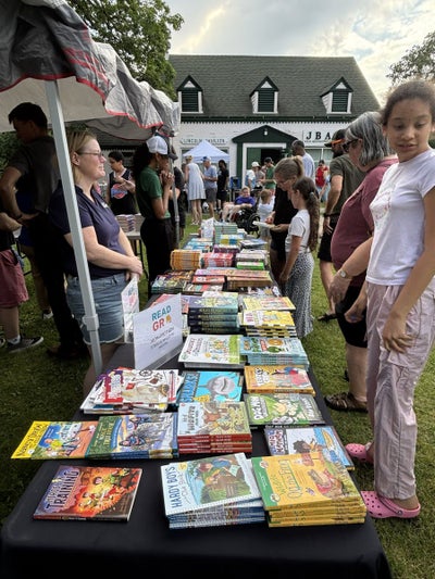 Families browsing free books near the Lincoln Park pavilion at Storytime in the Park