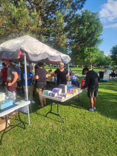 Volunteers setting out books under a canopy at Storytime in the Park